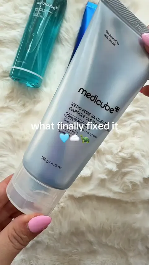 A hand holding the medicube cleanser bottle