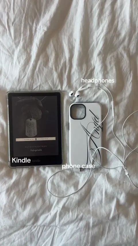 A Kindle, phone case and wired headphones on a white sheet, labeled